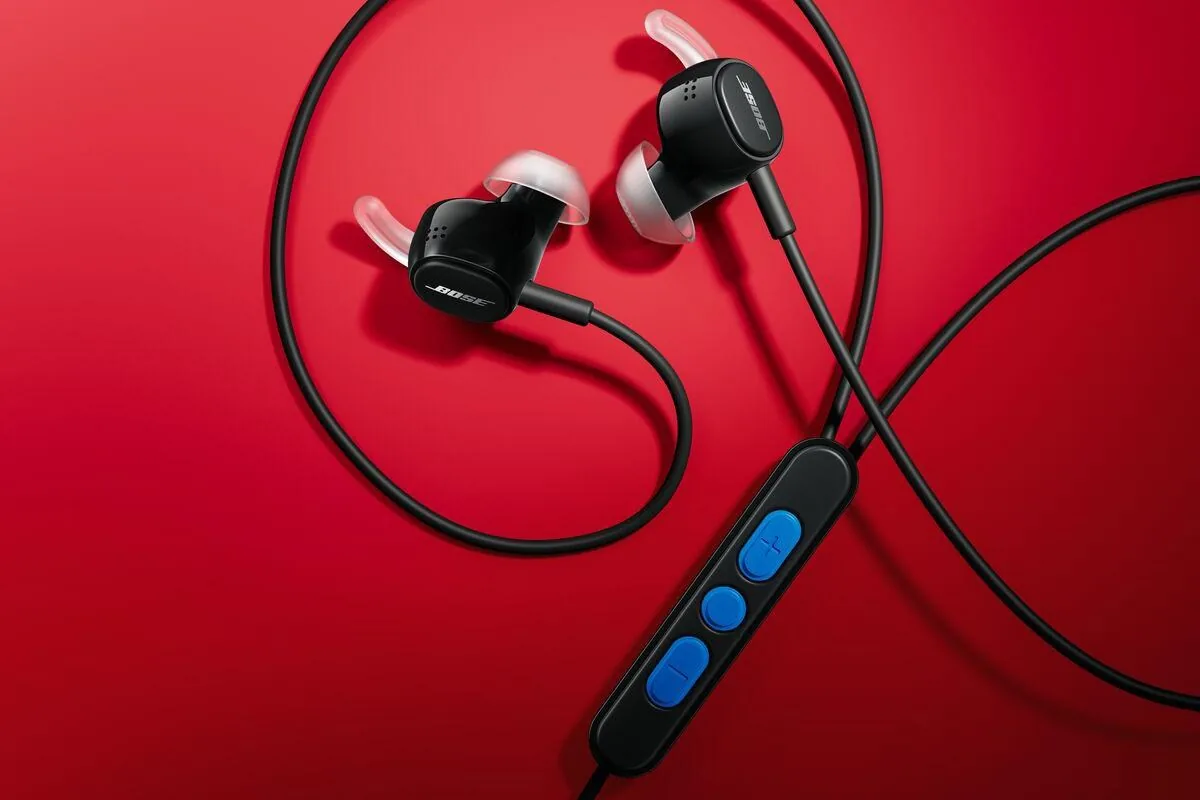 Bose wired earbuds displayed in black finish against a red background.