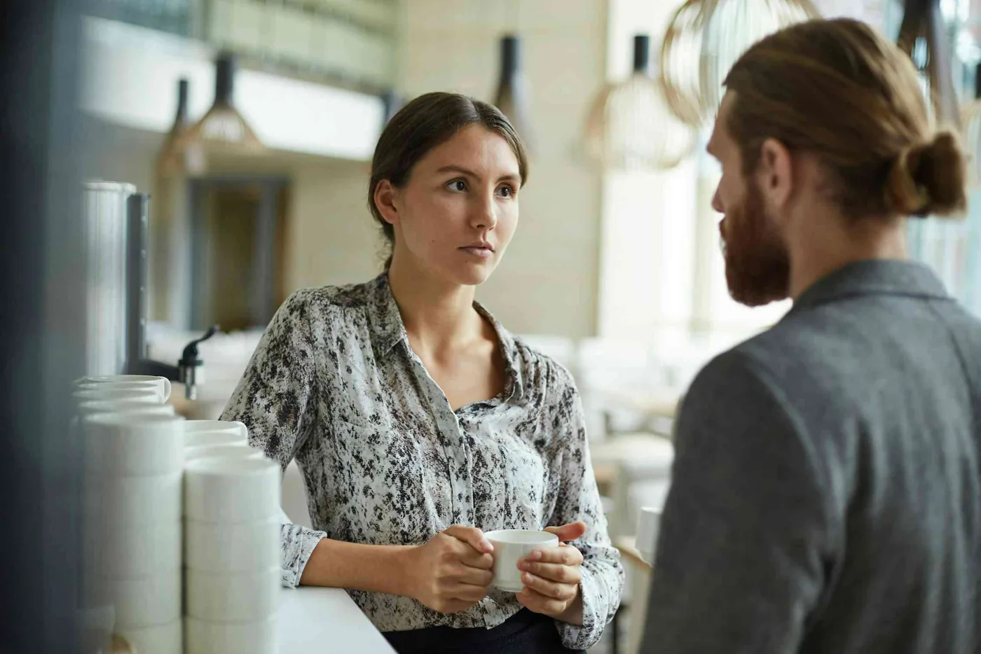 Two colleagues conversing in an office kitchen about accommodating chronic pain at work.