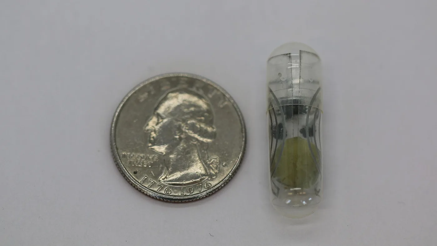 A wireless RFID tag powered by edible batteries shown beside a U.S. quarter for scale.