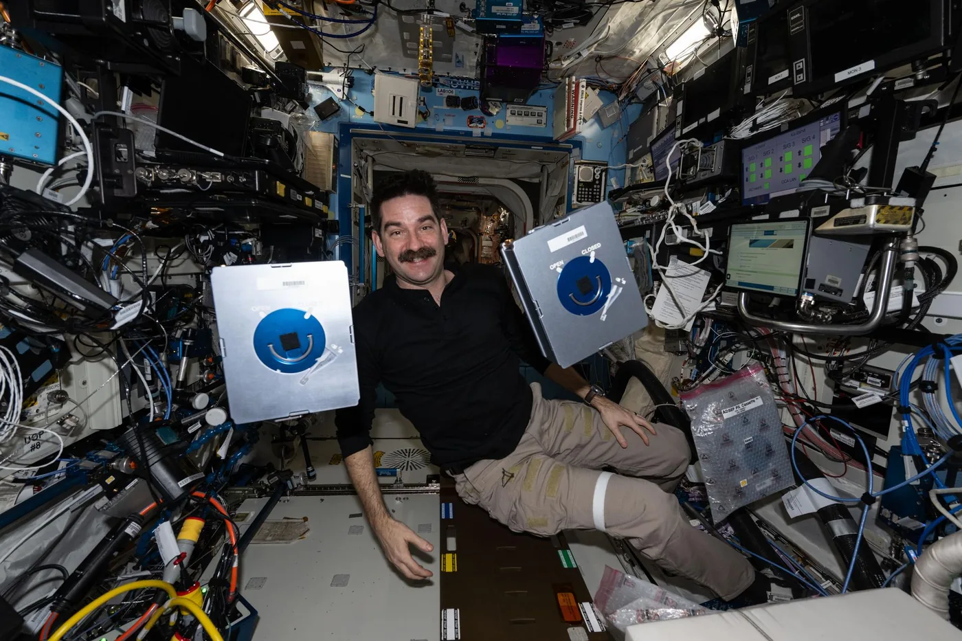 Astronaut Jack Hathaway holds sample cassettes evaluating space health technology aboard the International Space Station.