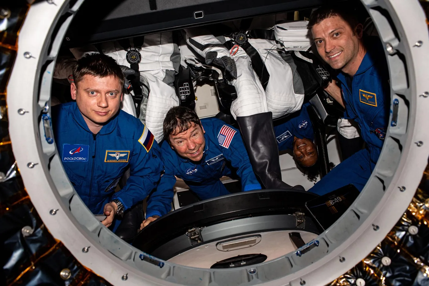 Commercial crew astronauts gather inside a spacecraft cabin during space health technology and rotation procedures.