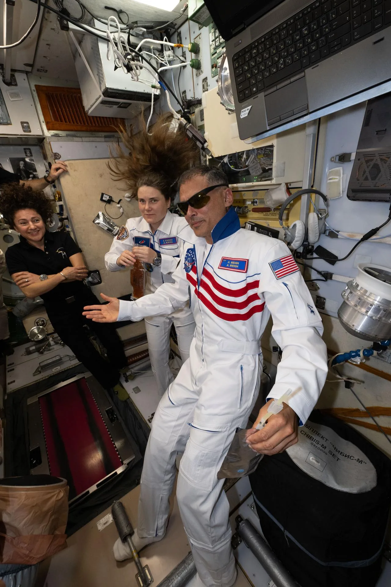 Expedition crew members smile together while supporting space health technology operations inside the orbital station.