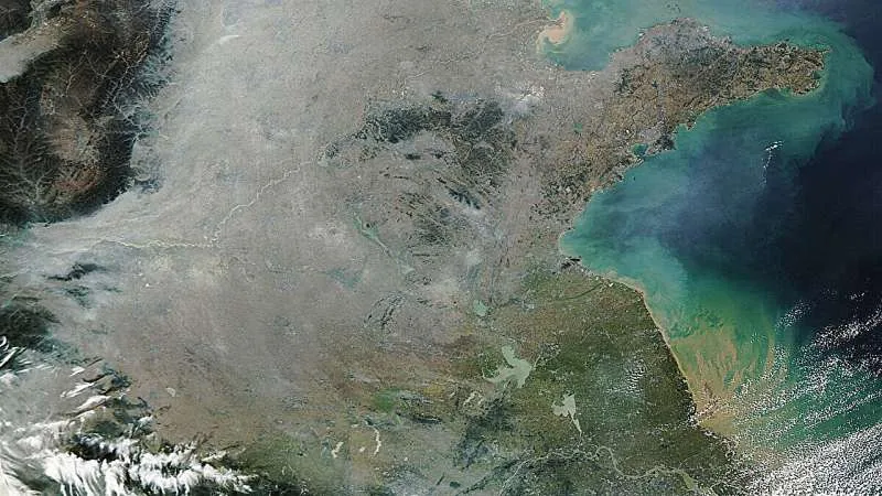 Satellite imagery documenting aerosol layers and atmospheric particles above coastal landmasses.