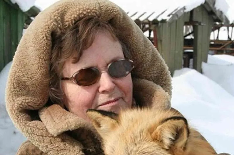 Researcher Lyudmila Trut holding a tame silver fox in snow