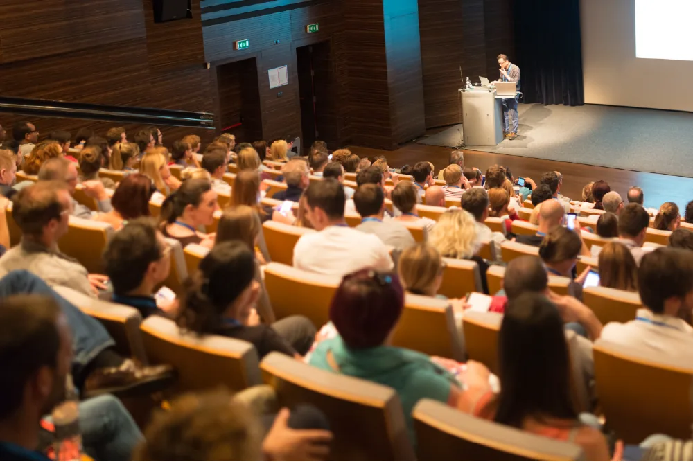 Audience in modern conference auditorium listening to translated audio