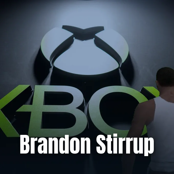 A illuminated Xbox logo on a dark wall with a person visible from behind.