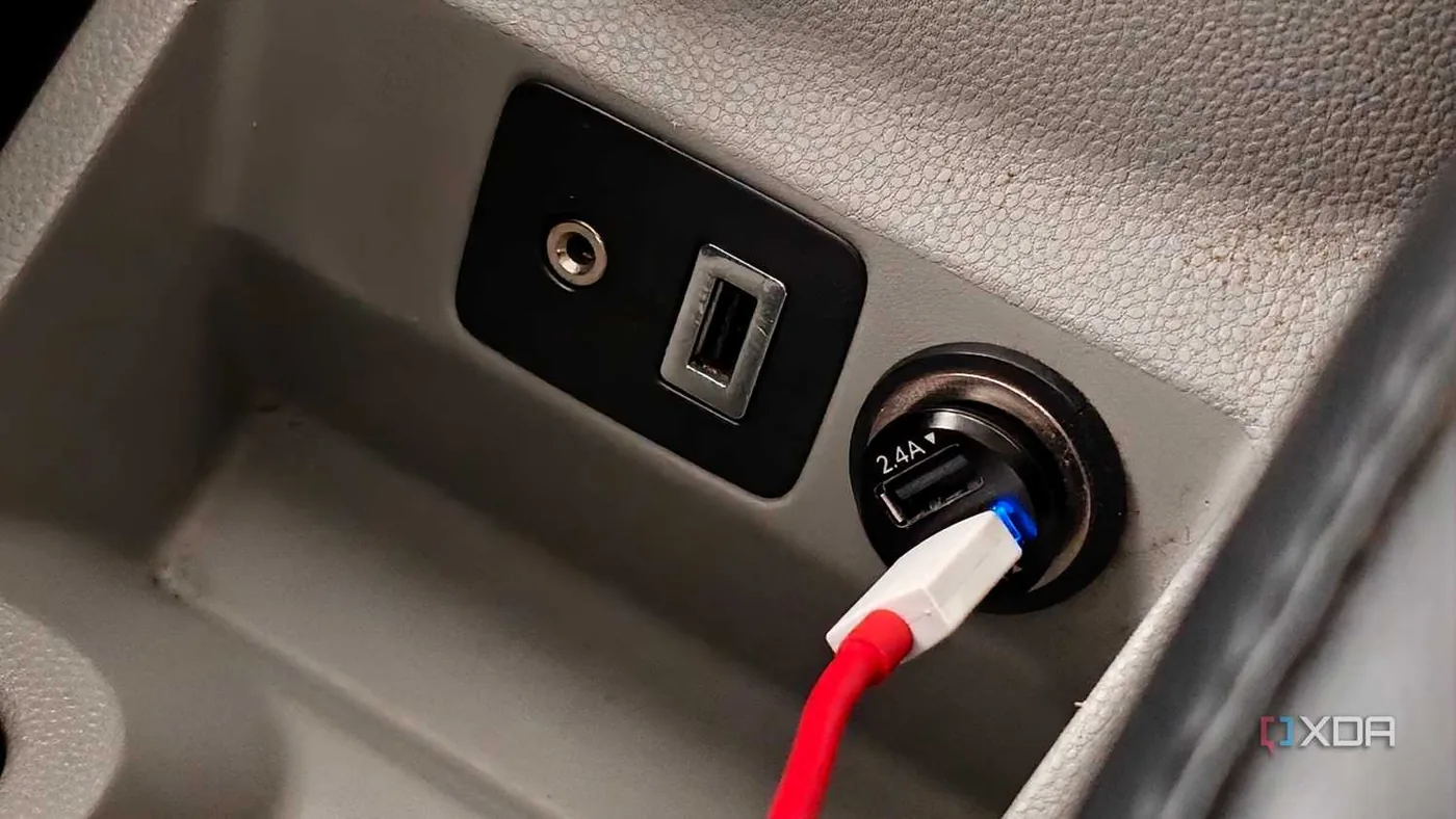 A smartphone charging from a 12V socket accessory in a vehicle