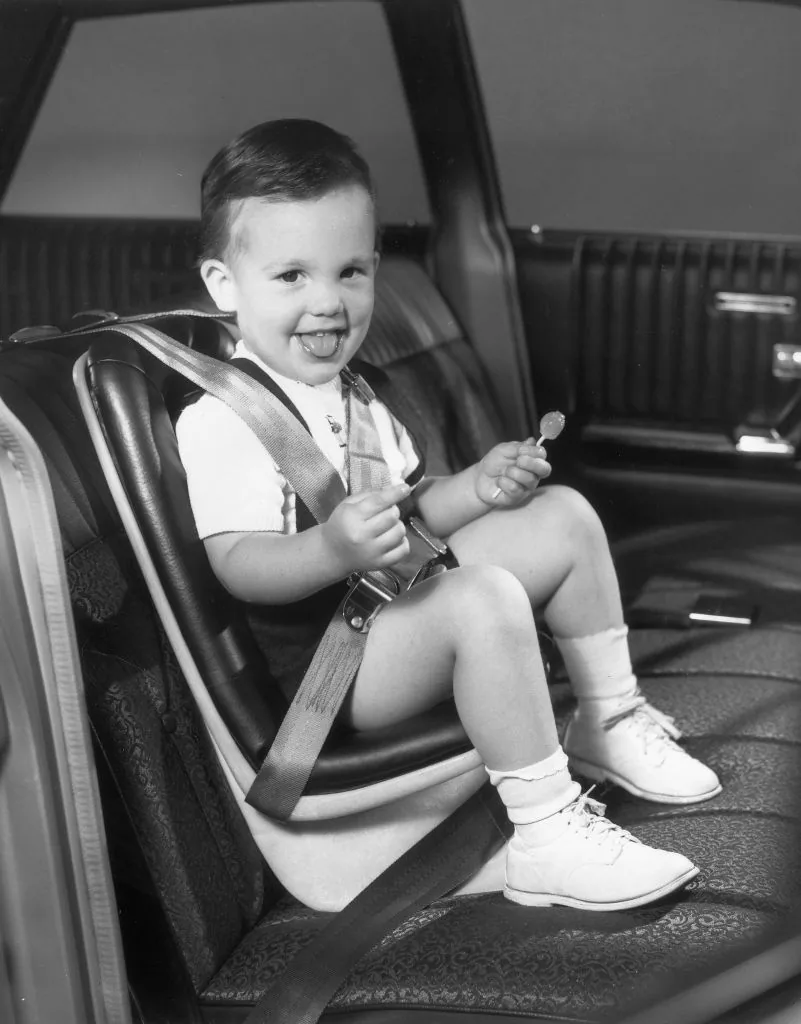 A boy sits in the Jeenay seat, an early rear-facing child restraint from the 1960s.