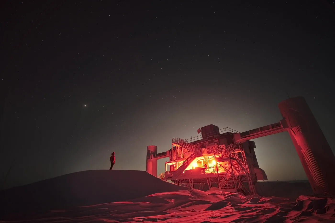 Exterior view of the IceCube neutrino detector facility across the Antarctic landscape.