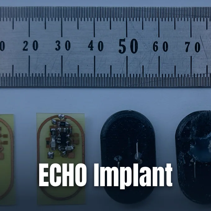 Small electronic implant prototypes displayed next to a steel metric ruler for scale measurement.