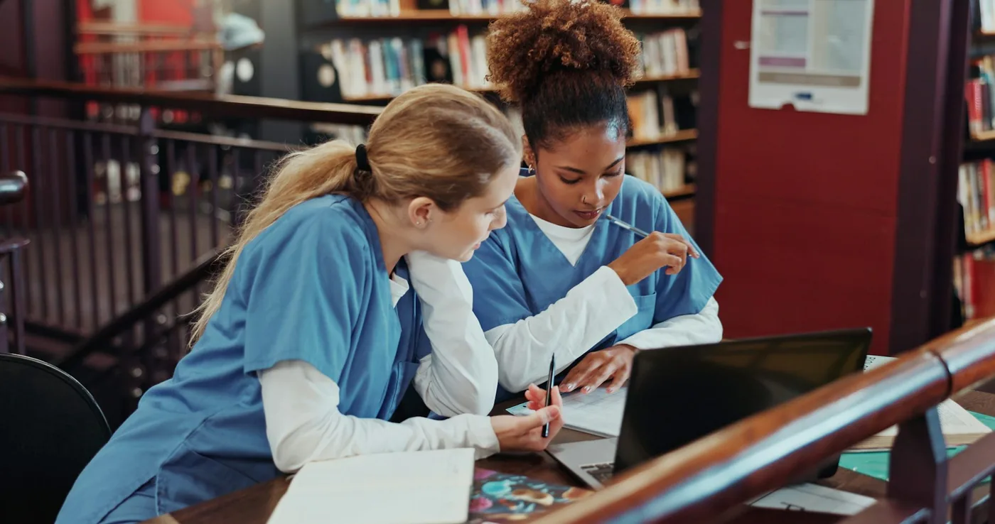 Healthcare students collaborating around medical study materials in a classroom setting