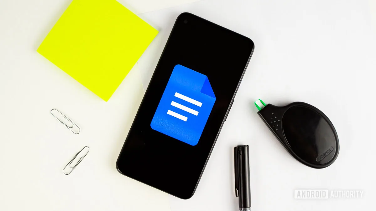 Google Docs logo on smartphone next to desk accessories