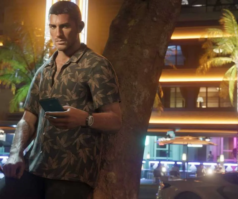 Protagonist Jason leaning against a tree while checking a mobile phone in Grand Theft Auto 6.