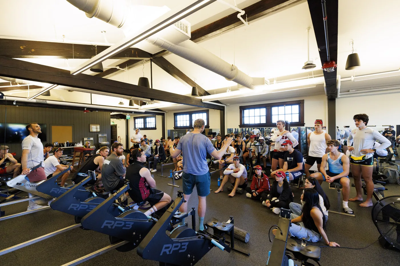 Hamish Bond gives advice to Harvard rowers in the workout room of Newell Boathouse.
