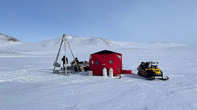 Field researchers collecting a sediment core from Toolik Lake to study Alaskan hillslope erosion