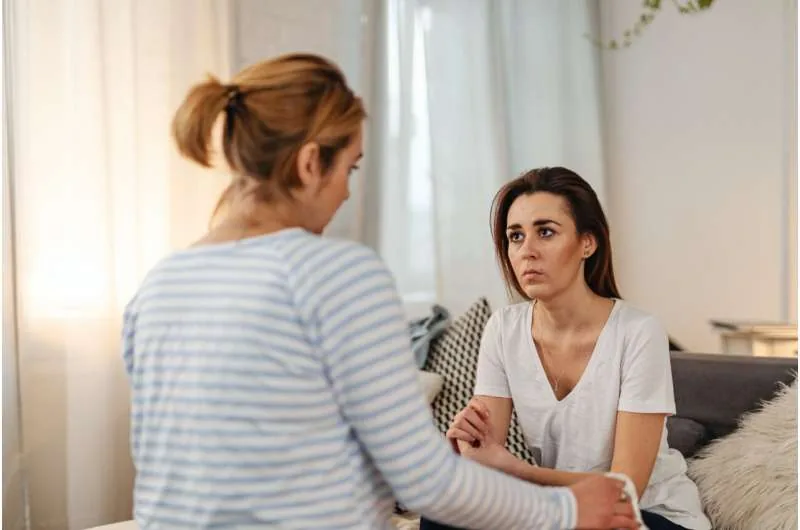 Two women having a serious conversation in a private setting.