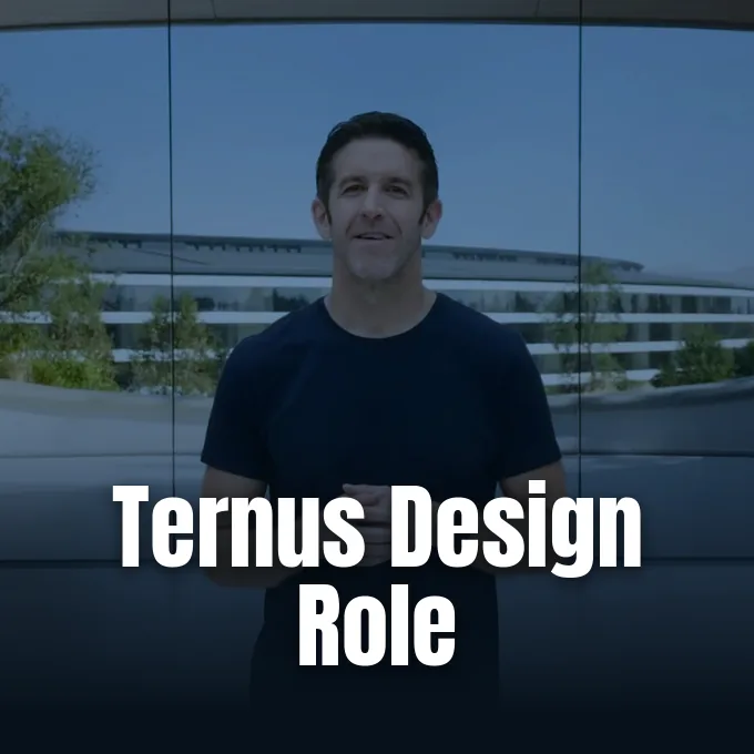 John Ternus stands smiling in front of the glass facade of Apple Park.