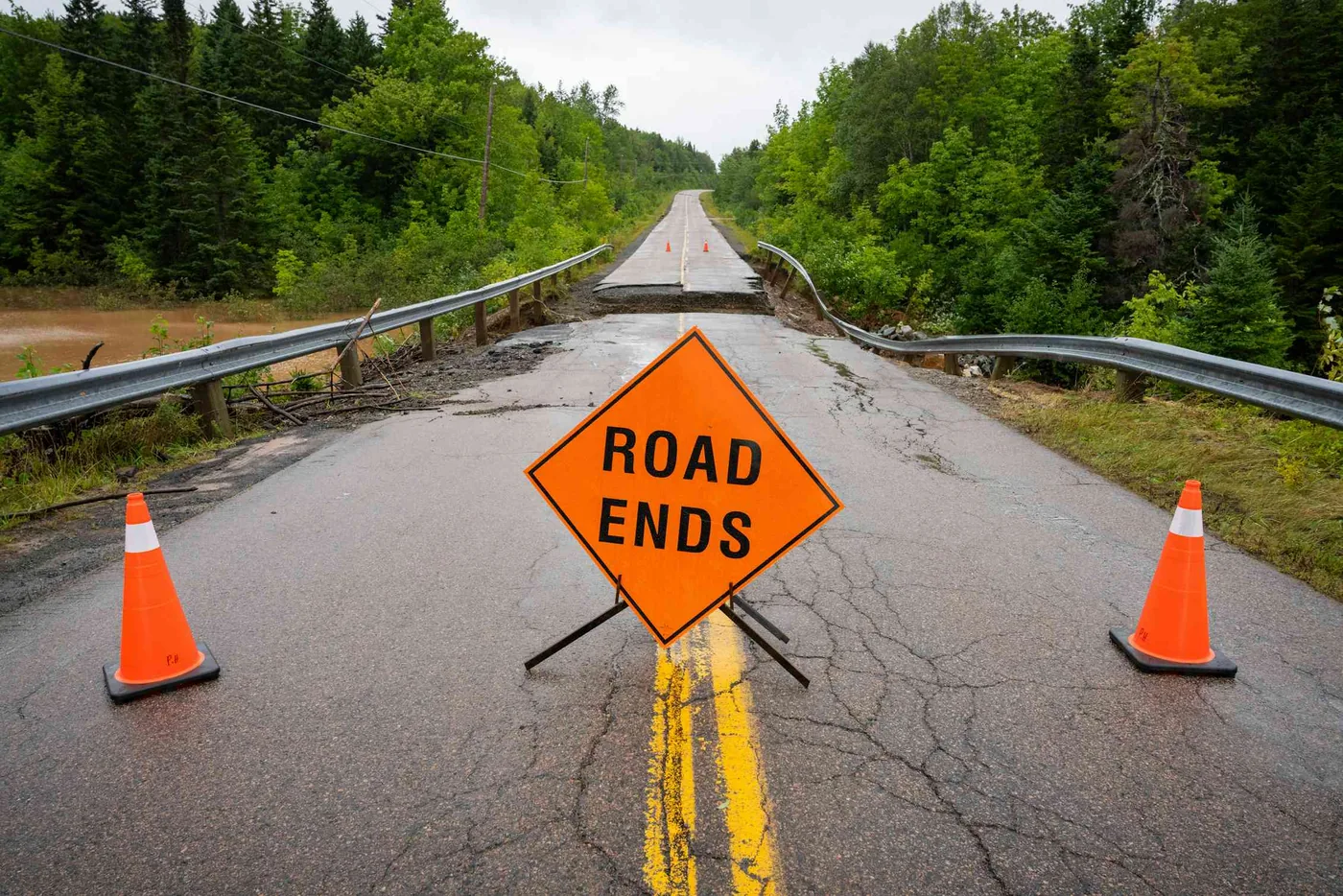 Washed out asphalt road showing severe climate damage to municipal transport networks