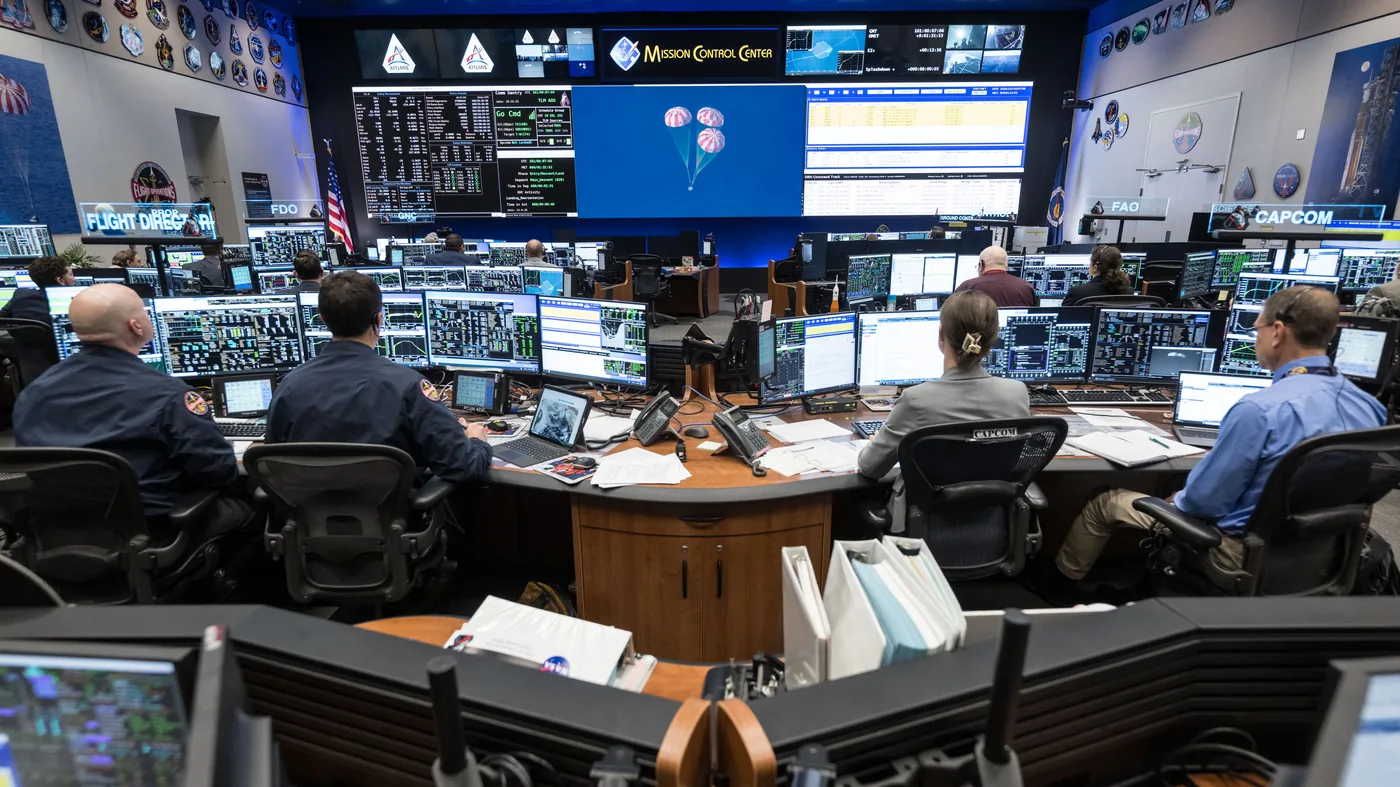NASA flight directors and flight controllers manage mission operations inside the Johnson Space Center control room.