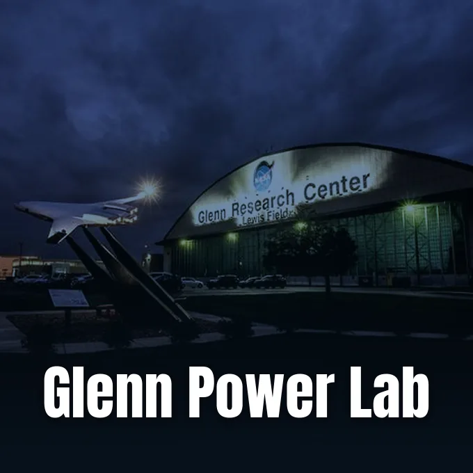 An illuminated hangar at NASA Glenn Research Center at dusk with an aircraft display outside