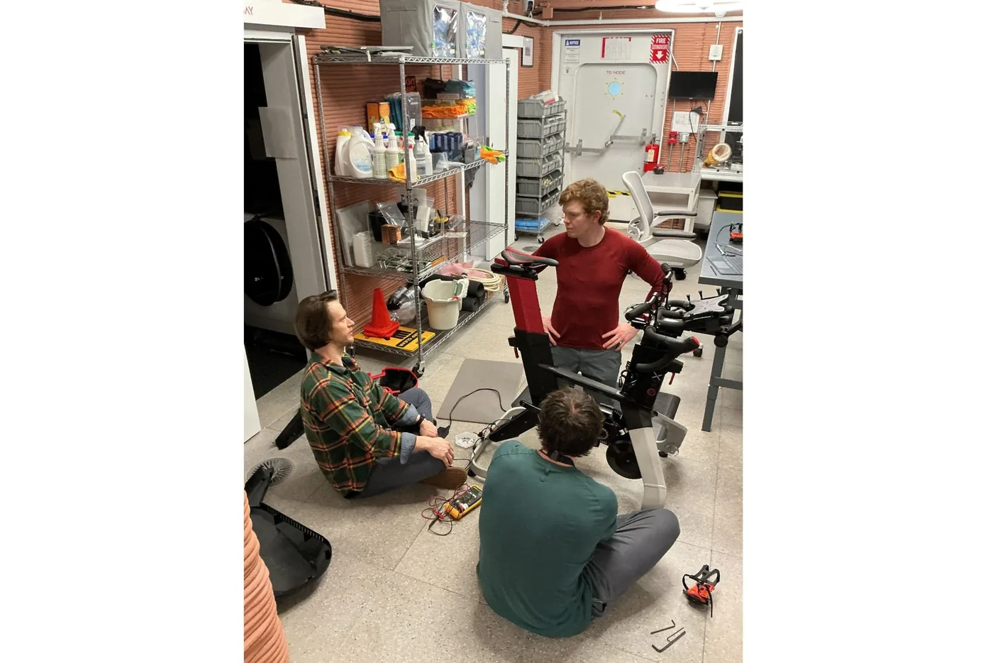 Crew members repairing their stationary exercise bicycle