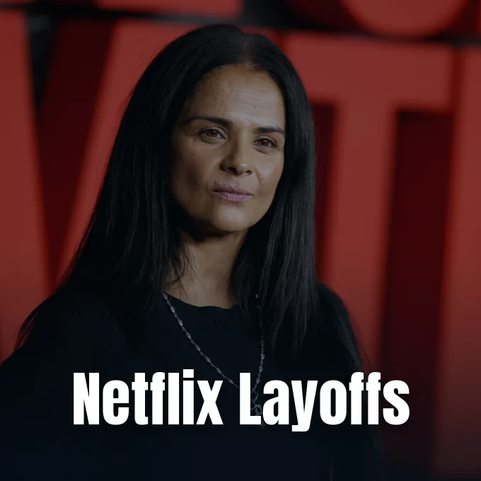 A portrait of Bela Bajaria looking forward in front of a red Netflix logo background.