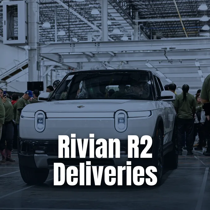 A white Rivian electric vehicle on an automotive assembly line surrounded by factory workers
