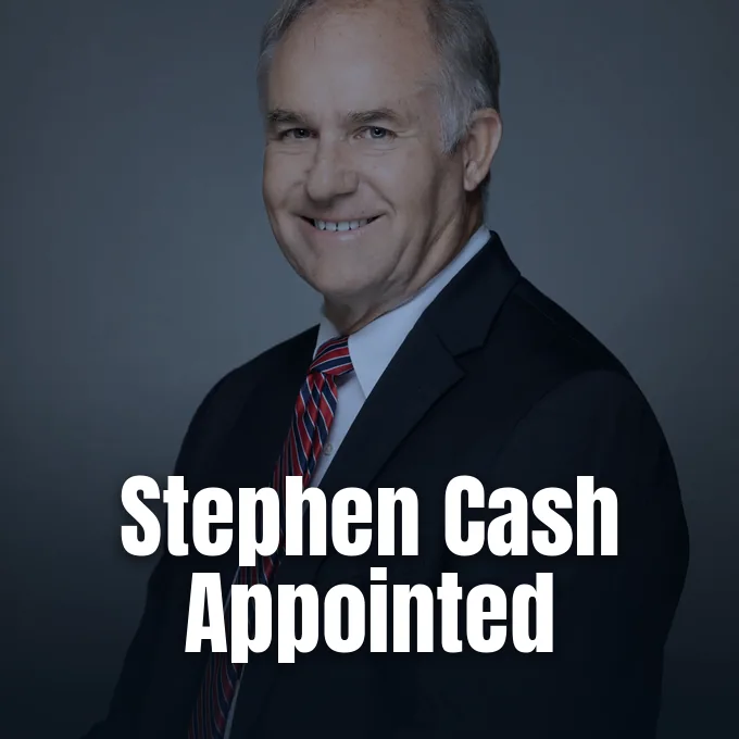 A portrait of Stephen Cash in a dark suit and striped tie against a plain backdrop.