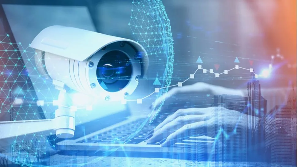 Surveillance camera positioned above an individual using a laptop computer.
